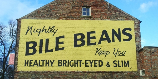 The side of a brick building on which is painted
		 a large yellow rectangle with the slogan "Nightly
		 bile beans keep you healthy, bright-eyed and slim."